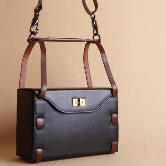 Structured Box Black Leather Shoulder Handbag with Dark Brown straps on a light yellow background 