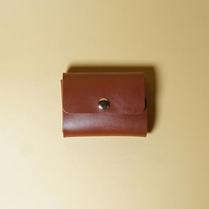 Tan Brown Leather Visting card case with a metal button on a beige background