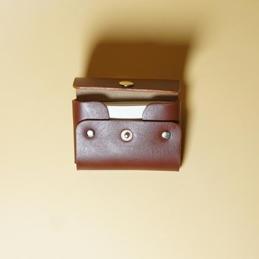 Tan Brown Leather Visting card case with a metal button on a beige background