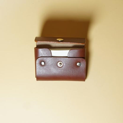 Tan Brown Leather Visting card case with a metal button on a beige background
