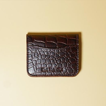 Maroon color crocodile textured cardholder on a beige background