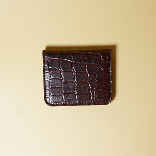 Maroon crocodile-patterned leather cardholder on a beige background