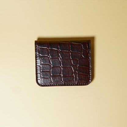 Maroon crocodile-patterned leather cardholder on a beige background