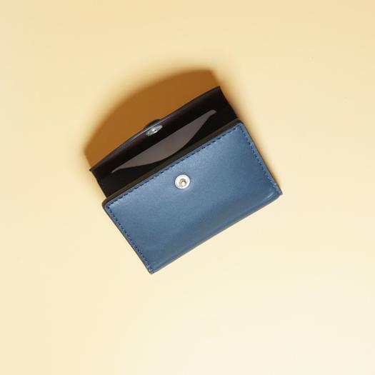 Blue wallet with a black interior and a gold button on a beige background