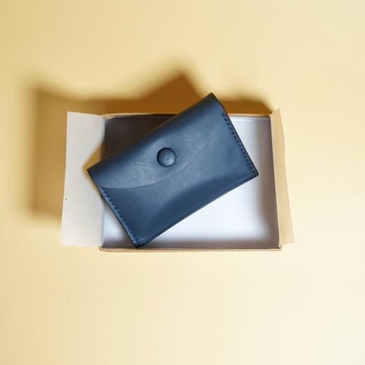 Blue leather wallet on a white box with a yellow background