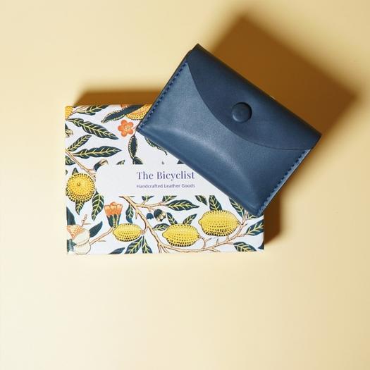 Blue leather wallet on a patterned box with 'The Bicyclist' branding