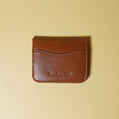 Tan leather cardholder wallet with 'The Bicyclist' branding on a beige background