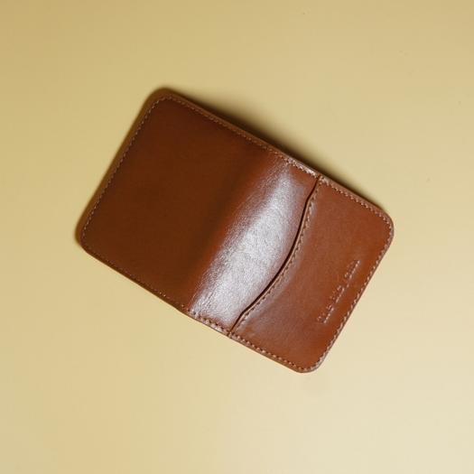 Tan brown leather wallet on a beige background