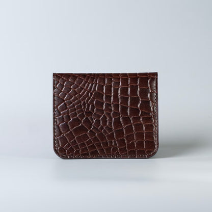 Full grain leather maroon slim bifold card wallet in corocodile leather texture with a card slot from The Bicyclist on a soft grey background 