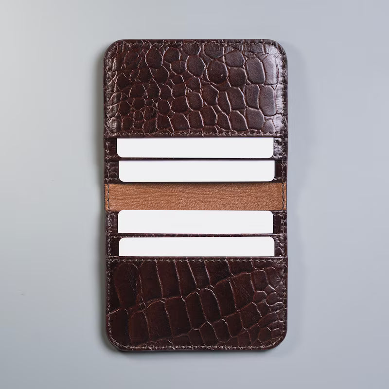 Open View of Full grain leather maroon slim bifold card wallet in corocodile leather texture with six card slot from The Bicyclist with white plastic cards inserted on a soft grey background 
