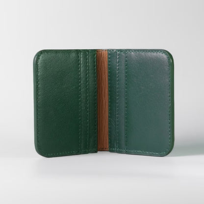 A dark green full grain leather wallet shown open, featuring a tan sheep leather lining down the center, set against a clean light gray background.