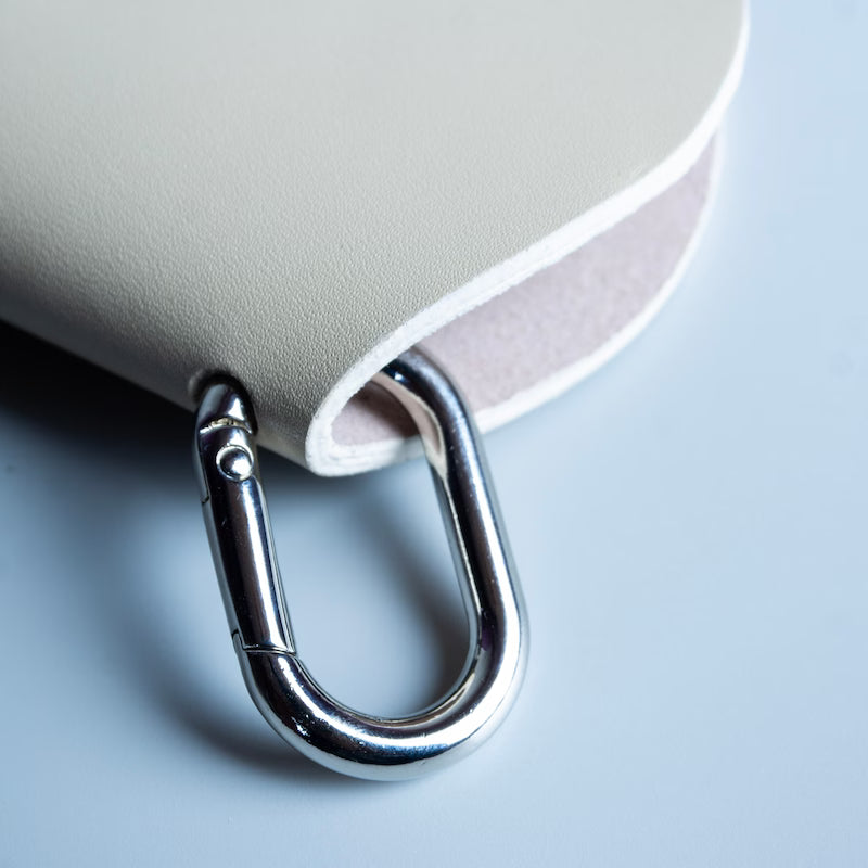 Close up view of a chrome plated metal carabiner hook attached on to a leather spectacle sleeve