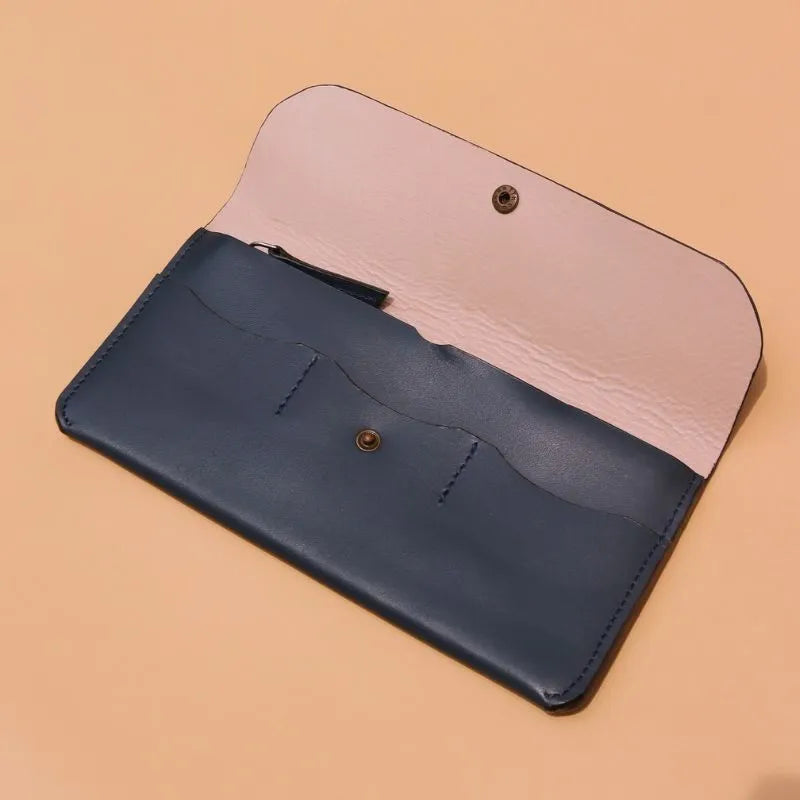 Handmade Leather Long Wallet for Women in Deep Blue on a peach background with the flap open and three card pockets with a snap button at the center and a light peach sheep leather lining 