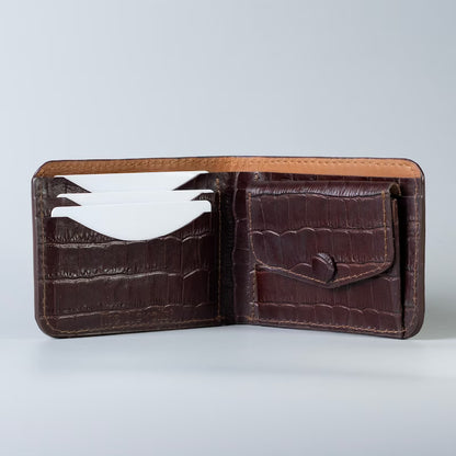 An open Maroon crocodile-embossed full grain leather bifold wallet with card slots and a coin pocket, made by The Bicyclist shown on a light gray background.