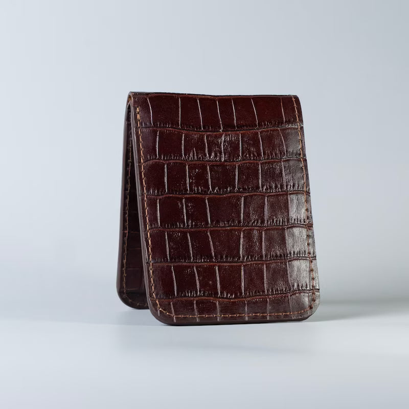 A maroon full grain leather wallet with a crocodile-embossed texture from The Bicyclist, standing upright on a light gray studio background.