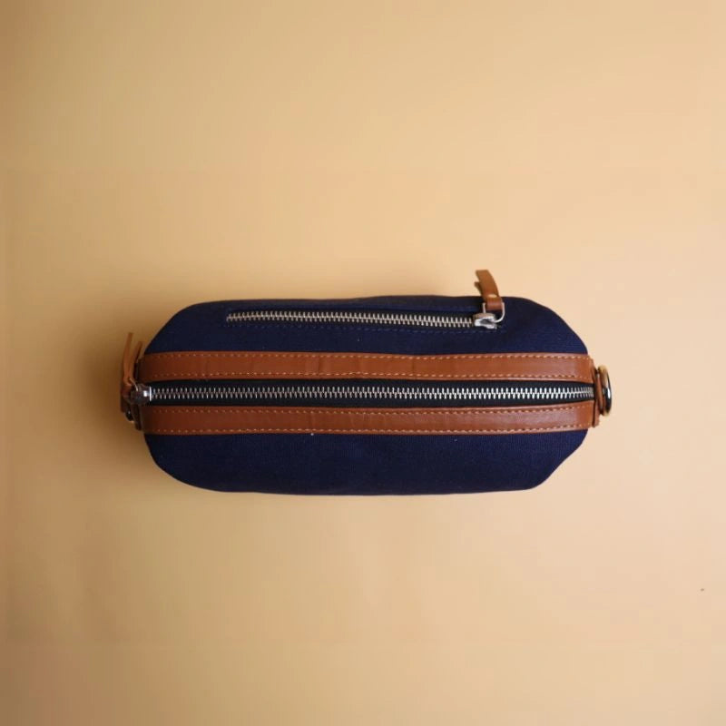 Top view of a navy blue cotton canvas and tan leather dopp kit with metal zip