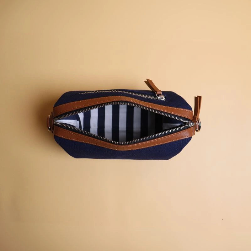 Top Open view of a navy blue cotton canvas and tan leather dopp kit with metal zip