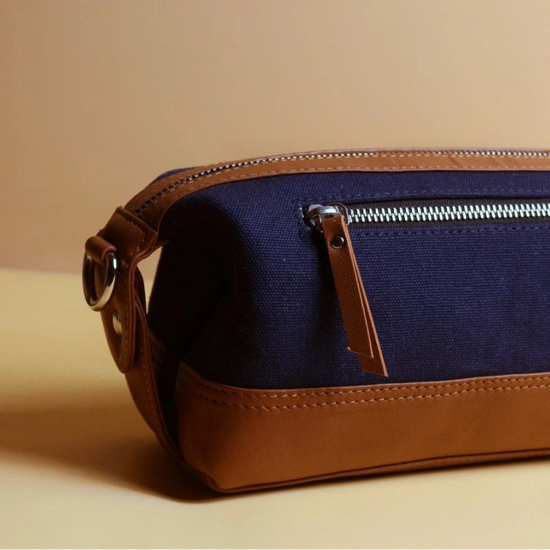 Detail view of a navy blue cotton canvas and tan leather dopp kit with metal zip