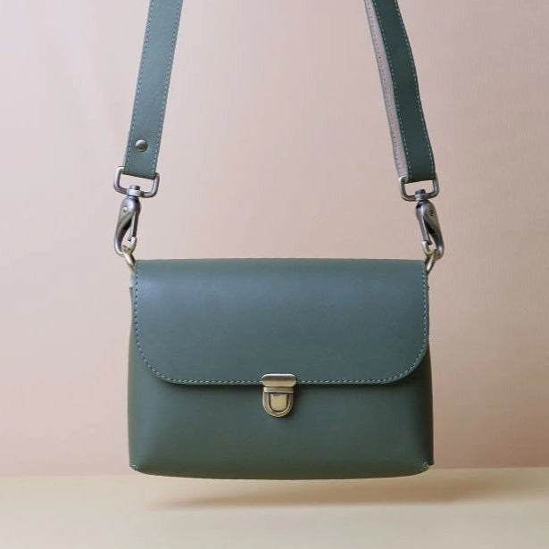 Front Upright image of a green leather crossbody shoulder sling bag with a flap and soft gold push lock and fittings