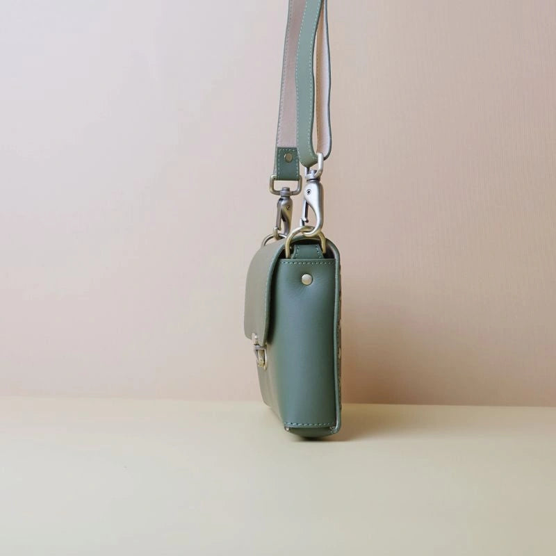 Side view of a green leather crossbody shoulder sling bag with soft golf fittings and a flap