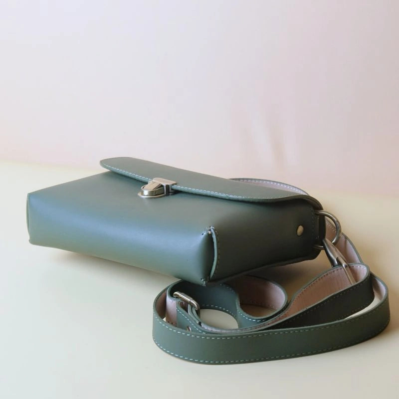 Bottom view of a green leather crossbody shoulder sling bag with detachable and adjustable straps