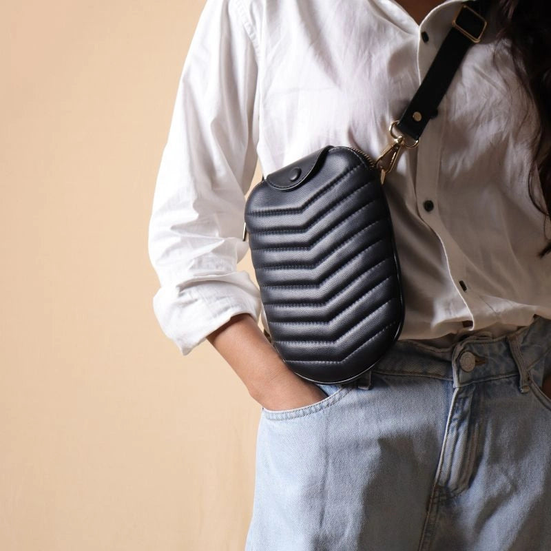 Woman in a white shirt carrying a small black quilted leather shoulder sling bag around her chest 