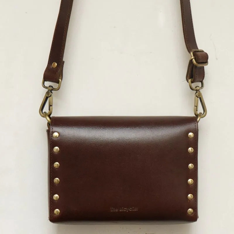 Back View of Dark Brown Leather Crossbody Sling Bag with Light Gold fittings on a white background