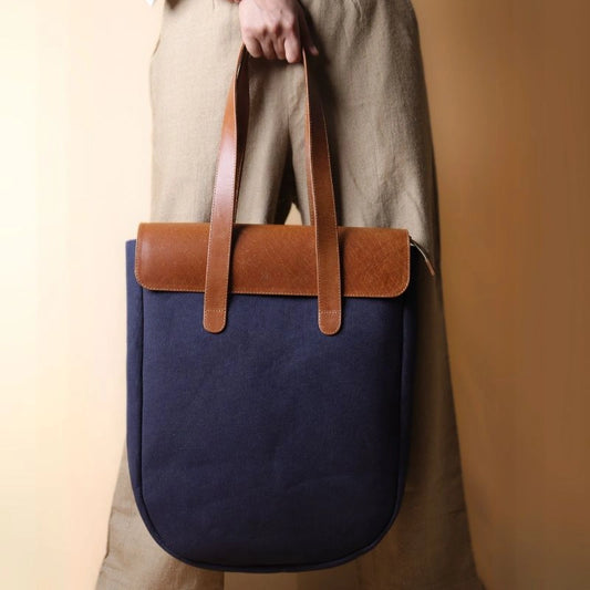 Woman in beige trousers holding a Deep Blue Tote bag with Tan Leather Flap and Tan Leather Straps in her hand