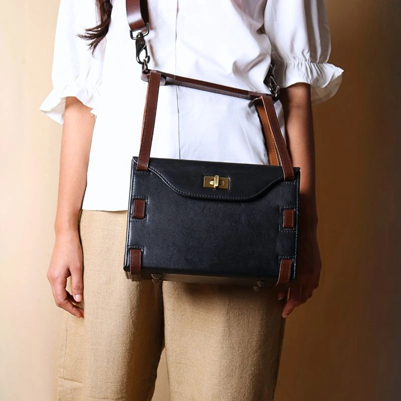 Structured Box Black Leather Shoulder Handbag with Dark Brown straps carried by a woman wearing a white shirt as a crossbody bag