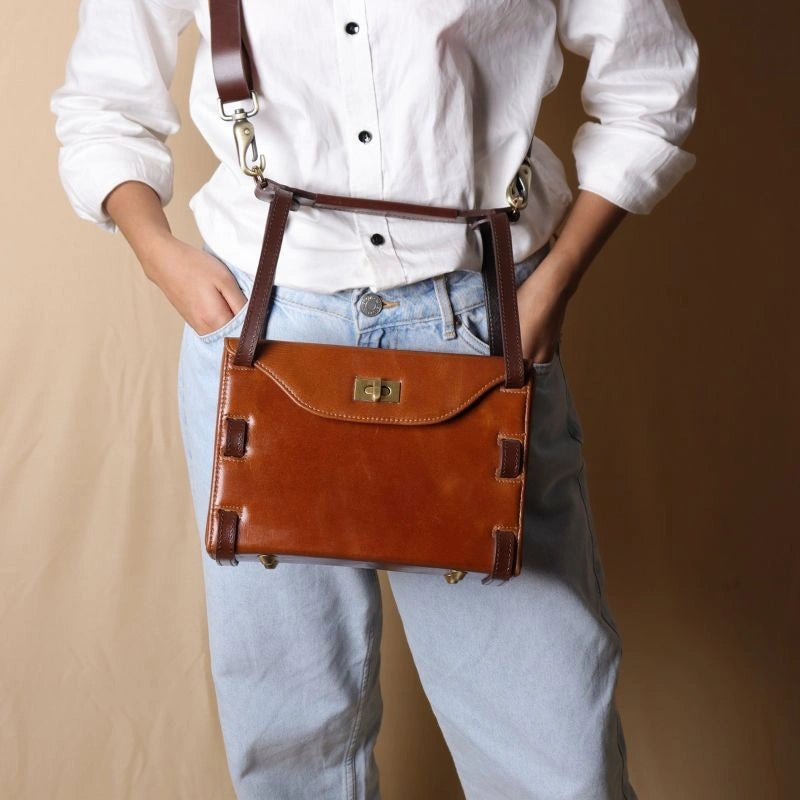 Front View of Woman in a White shirt carrying a structured box leather crossbody sling bag in tan with dark brown straps around her shoulder