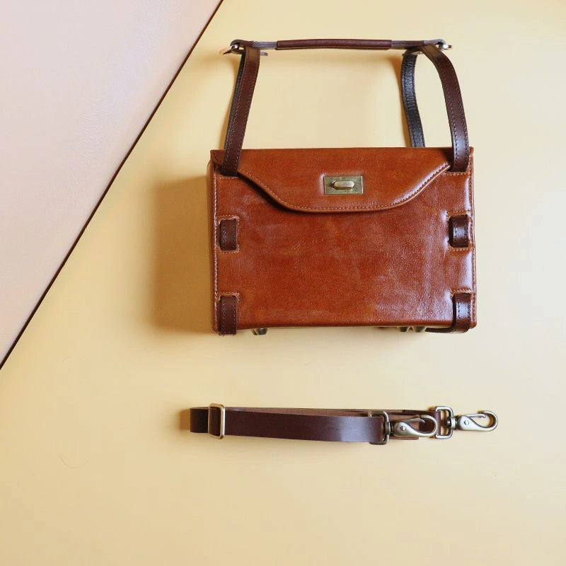 Front Flat Top View of Tan Leather structured box crossbody handbag with dark brown straps and golden twist lock and detached dark brown straps 