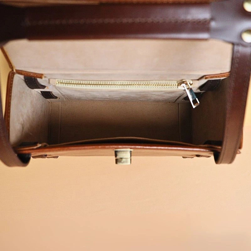 Top Open View of a Leather Structured Box Crossbody Sling Bag in Tan with dark brown Harness Leather Straps, light beige felt lining, internal zip pocket with a golden zip and a golden twist lock