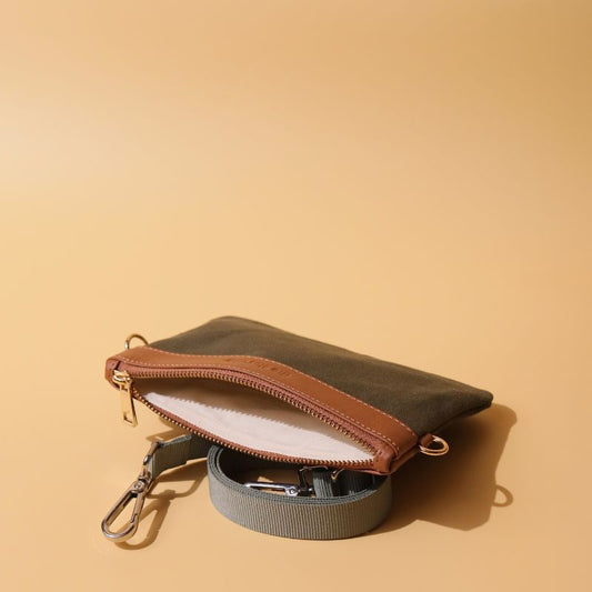 A mini crossbody side sling pouch with removable straps in dark green canvas and tan sheep leather with metal fittings in plated chrome finish open view