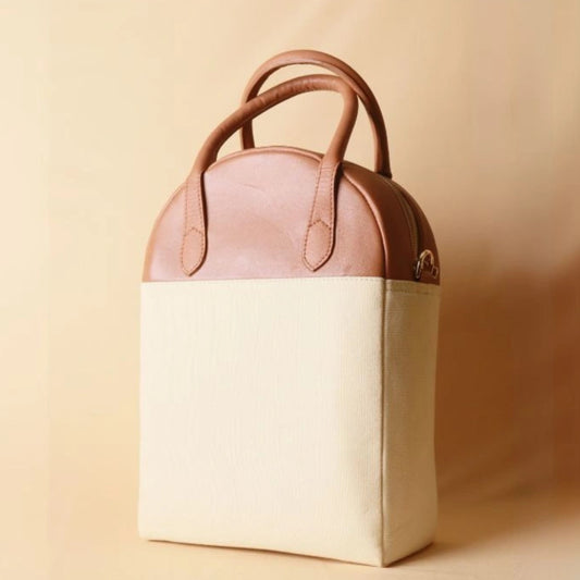 Front view of a top handle white canvas and tan leather office handbag 