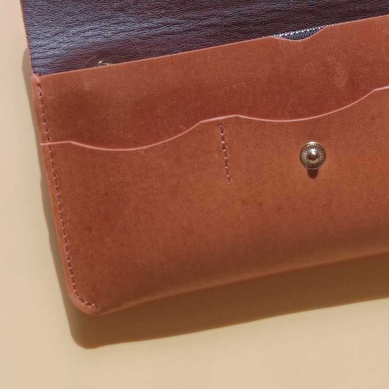 Detailed view of stitching in a leather long wallet for women in tan 