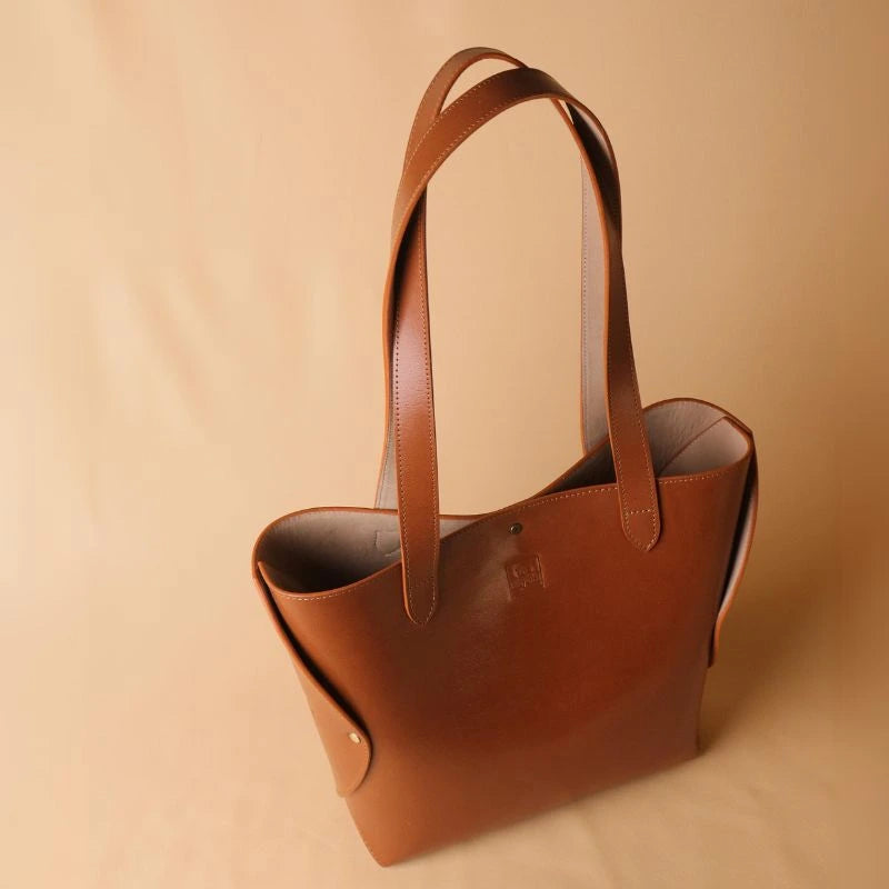 Top view of a structured leather tote bag in tan with upright handles and no zipped closure