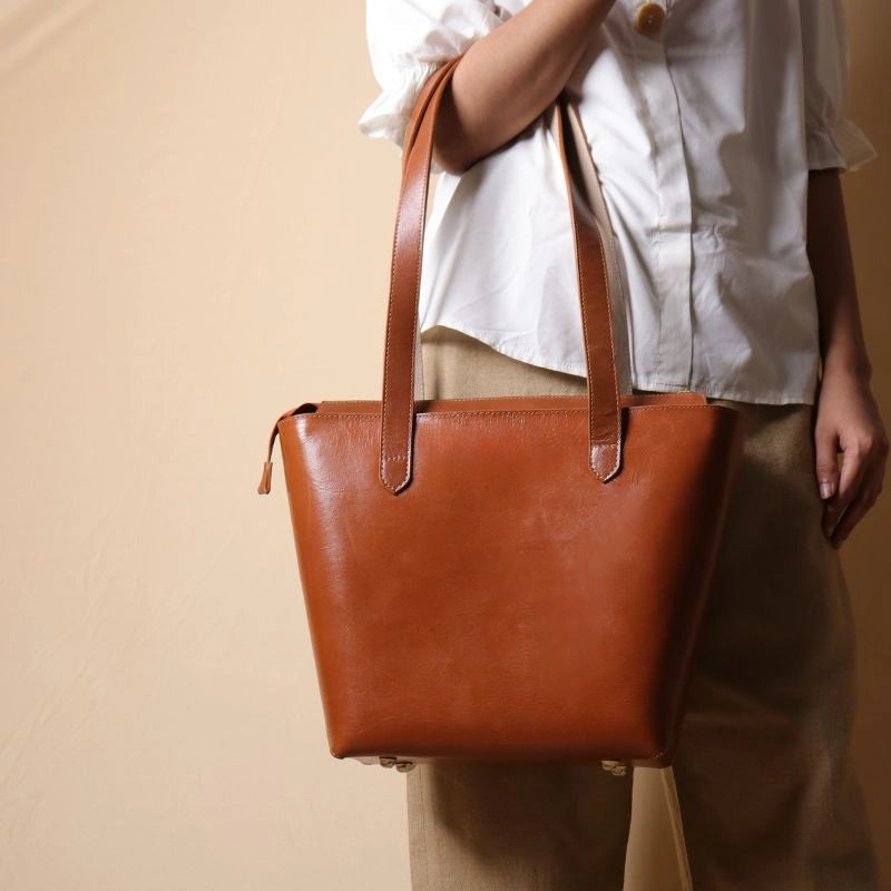 Leather Tote Handbag in tan held by a woman  in her hand wearing a white shirt