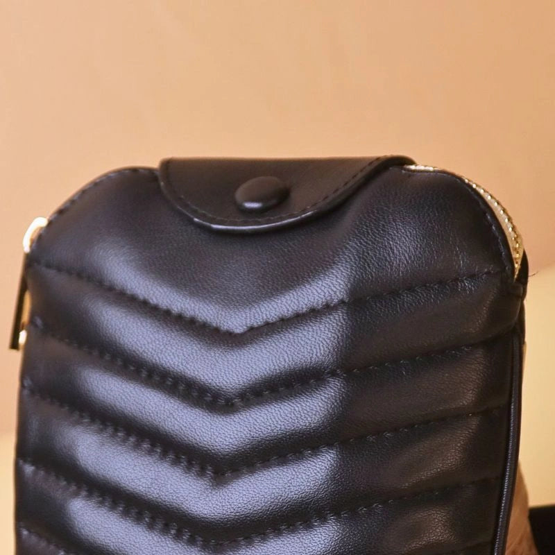 Detailed view of a small black leather purse with quilted finish, with a flap and a leather covered button.