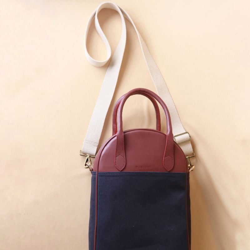 Hancrafted Canvas and Leather handbag-deep blue canvas body with maroon grain leather top-beige felt lining-adjustable and removable white shoulder straps-gold plated metal fittings-front top view-The Bicyclist